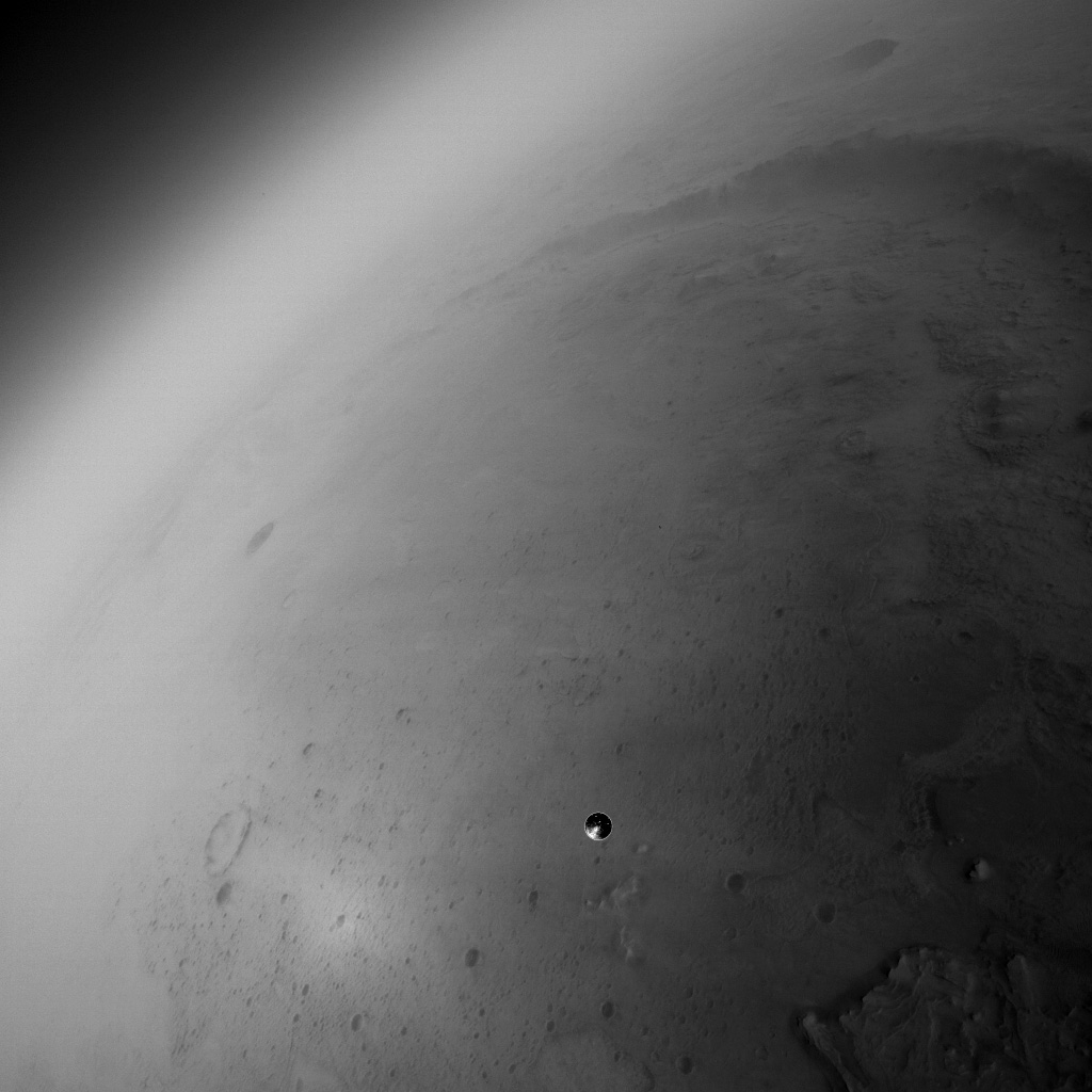 Fisheye photo from the Perseverance Lander Vision system camera. Jezero Crater nearly fills the image, with the delta located at bottom right. The lander's heat shield is falling away near image center.