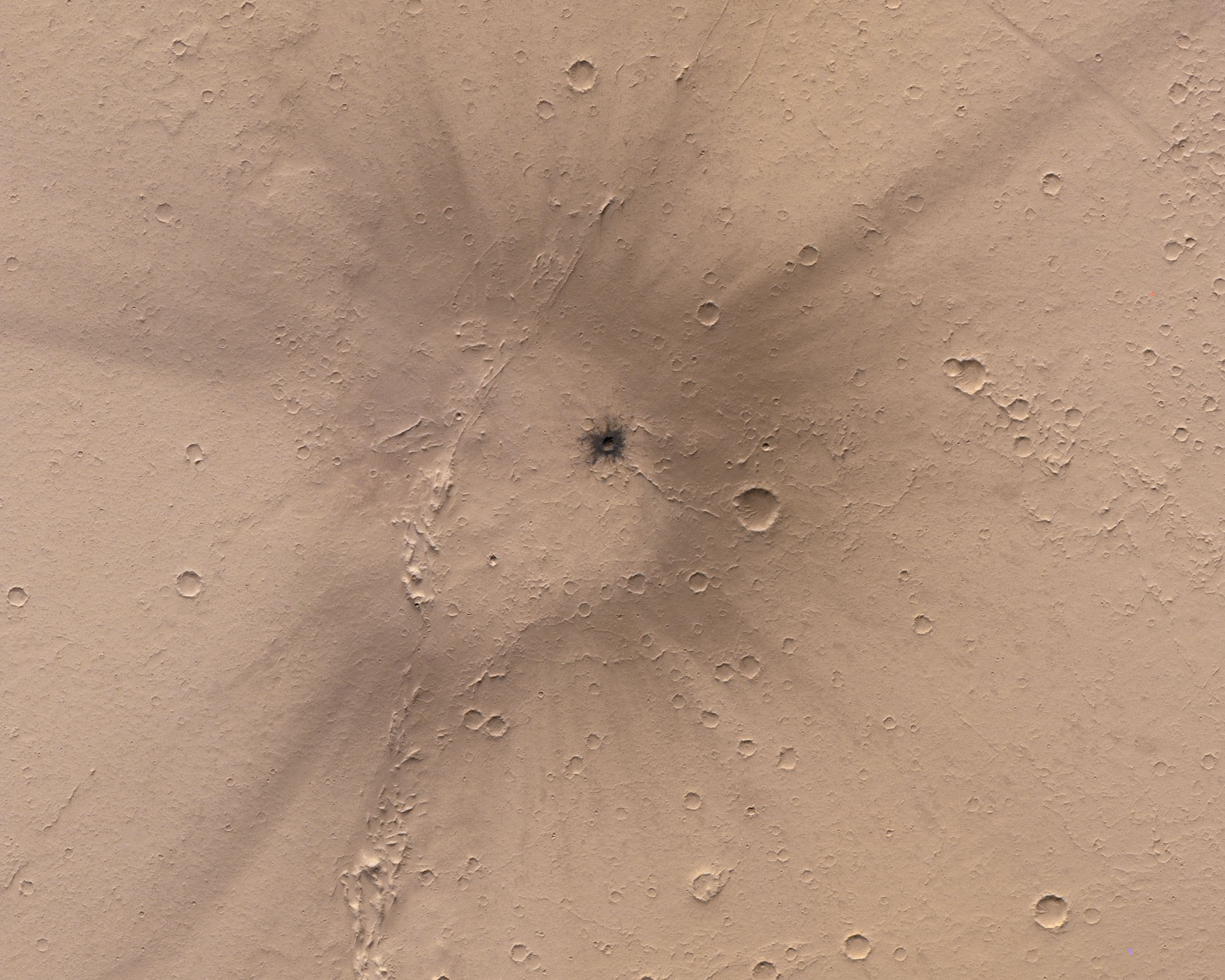 A fresh looking impact site in Mars' Tharsis region. A small region of dark material is surrounded by a larger halo and rays of dark material.